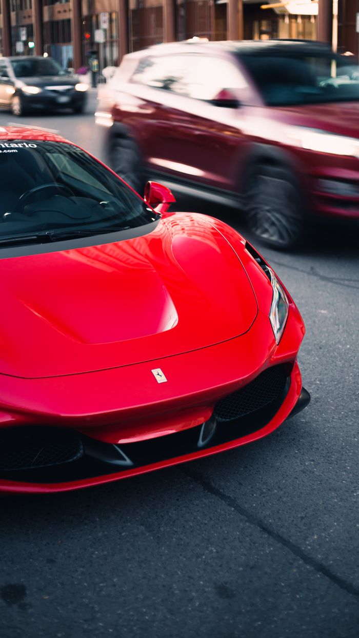 A striking red Ferrari supercar parked on a bustling Toronto street, capturing urban elegance.